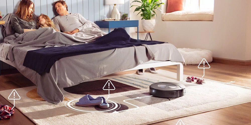 People in bed with Roomba on the ground